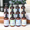 Twelve bottles of high-end lotions by Whole Self Aromatherapy atop a piece of wood with spa towels on one side and a flower on the other.